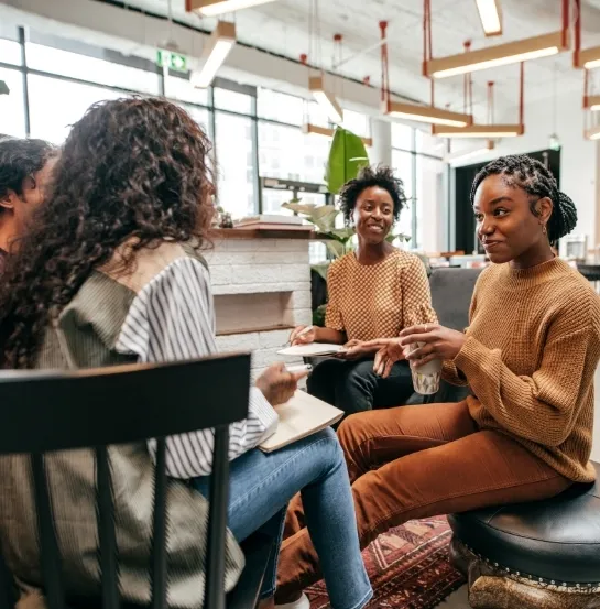 Grupo de profesionales diversas conversando de forma distendida en un espacio de trabajo moderno, representando la atracción y retención de talento en empresas sostenibles