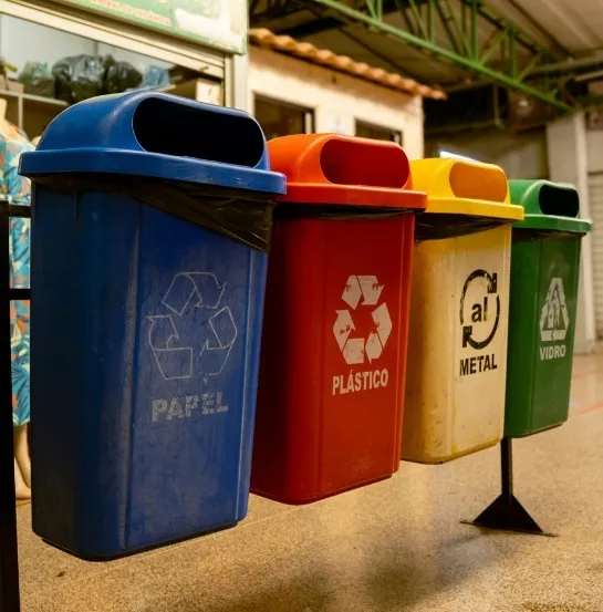 Cuatro contenedores de reciclaje de colores —azul, rojo, amarillo y verde— para papel, plástico, metal y vidrio, representando la correcta separación de residuos como base de la sostenibilidad empresarial