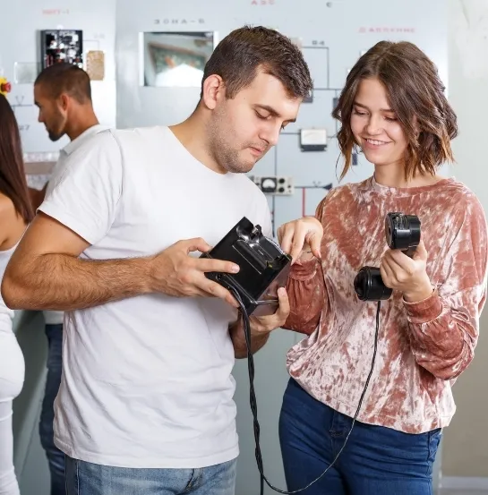 Compañeros de trabajo manipulando un dispositivo técnico durante una sesión de team building, representando el Escape Room para equipos