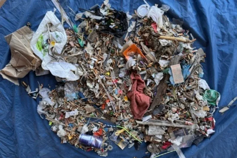 Vista aérea de todos los residuos recogidos extendidos sobre una lona azul durante una limpieza de playa de Go Zero Waste, mostrando la tipología y cantidad de basura marina recogida