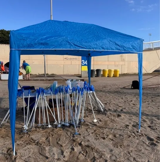 Carpa azul de Go Zero Waste en la playa con pinzas y materiales de limpieza preparados, representando la organización y metodología de las actividades de limpieza de costa