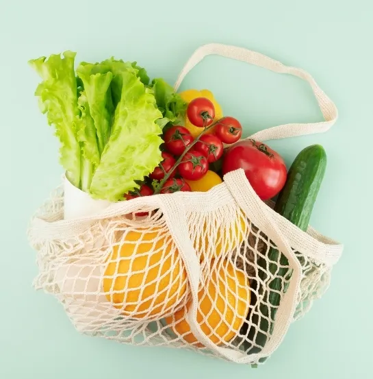 Bolsa de malla reutilizable llena de frutas y verduras frescas, representando el consumo responsable y la cultura de oficina sostenible como temática de formación ambiental empresarial