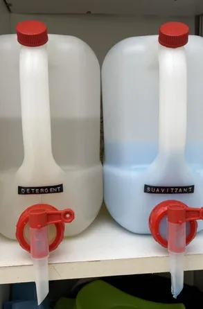 Dos dispensadores a granel de detergente y suavizante con grifos rojos en un comercio local