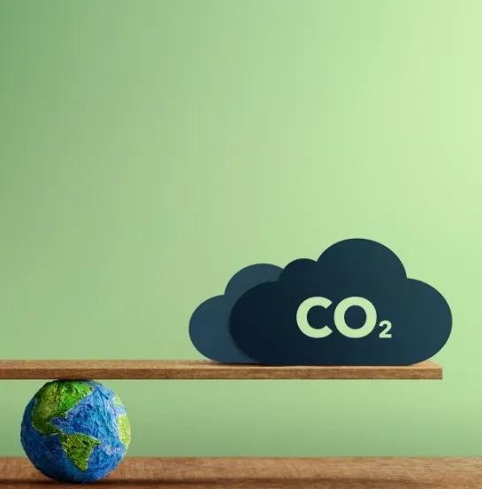 Balanza con un globo terráqueo y una nube de CO₂, representando el equilibrio necesario entre actividad empresarial y reducción de emisiones en la formación sobre huella de carbono