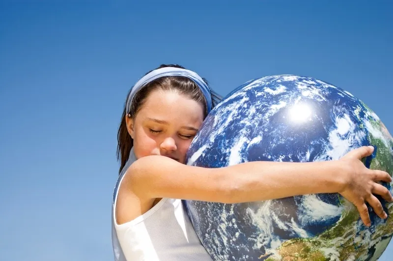 Girl hugging a globe against a blue sky, illustrating SDG 13 on climate action