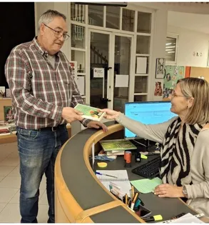 Hombre recibiendo un folleto de la campaña de manos de una trabajadora en un mostrador de atención