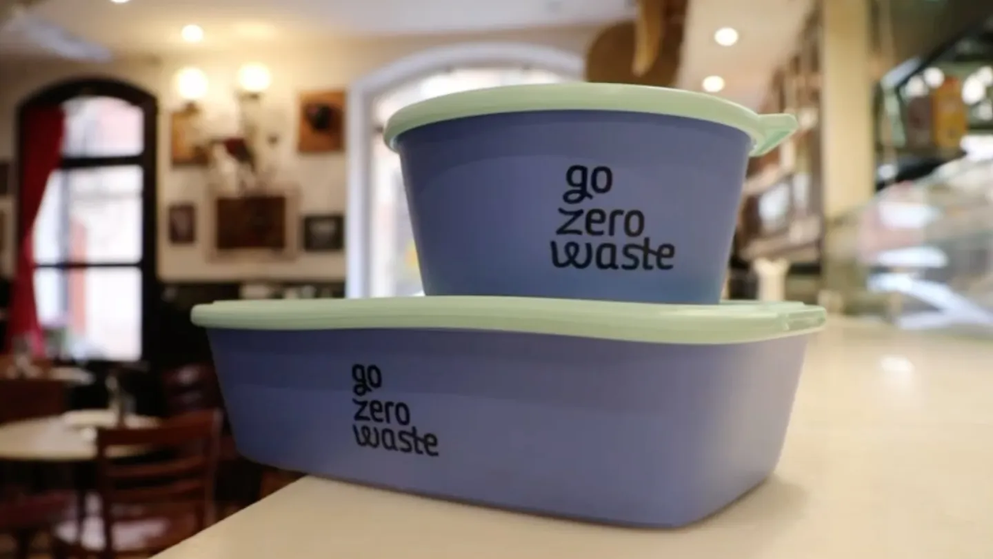 Dos envases reutilizables Go Zero Waste azules con tapa verde sobre la barra de Bodega La Peninsular