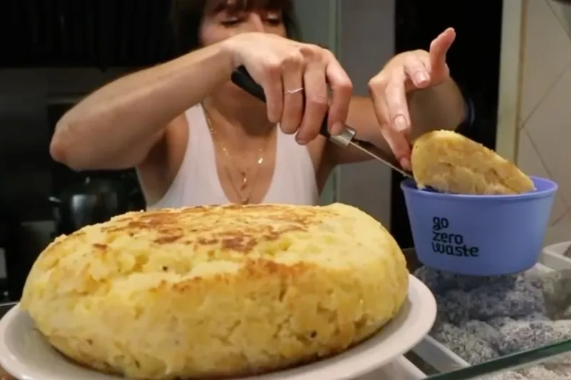 Persona sirviendo una porción de tortilla de patatas en un envase reutilizable Go Zero Waste