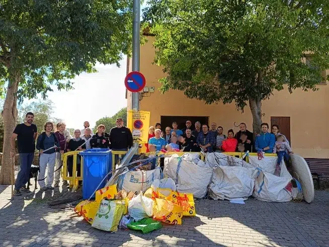 Grupo de voluntarios posando junto a los residuos recogidos durante una jornada de limpieza del entorno